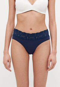 Chiloți din bumbac bleumarin cu talie din dantelă florală. Textură moale și potrivire elastică, având detalii intricate din dantelă pe marginea superioară.