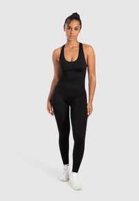 Zwarte eenpiece jumpsuit met een ronde hals en racerback ontwerp, gemaakt van een gladde stof; de aansluitende vorm benadrukt de silhouette.