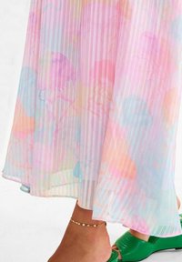 Gonna maxi plissettata in colori pastello con motivi di meduse. Realizzata in materiale leggero e trasparente con strisce verticali.