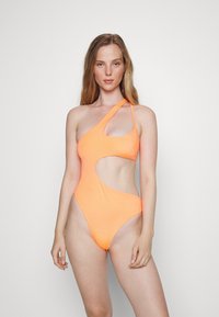 Maiô de um ombro, na cor laranja neon, com detalhes recortados, textura suave, abertura alta nas pernas e design minimalista.