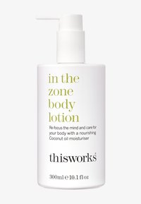 Weiße Kunststoffpumpe mit Körperlotion und grünem Text. Das Etikett lautet "In the Zone Körperlotion" mit Details zur Feuchtigkeitscreme auf Kokosnussöl. 300ml.