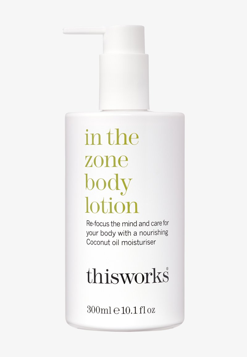 Weiße Kunststoffpumpe mit Körperlotion und grünem Text. Das Etikett lautet "In the Zone Körperlotion" mit Details zur Feuchtigkeitscreme auf Kokosnussöl. 300ml.
