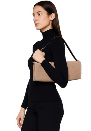 Borsa in suede beige con forma rettangolare, tracolla nera e texture liscia. Il modello tiene la borsa contro un outfit nero, mettendo in risalto il suo design.