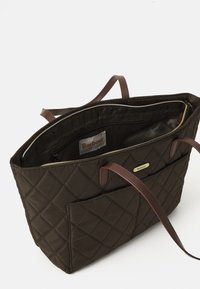Donkerbruine gewatteerde tote bag met een voorzak, twee slanke leren handvatten, en zichtbaar merklogo aan de binnen- en buitenkant.