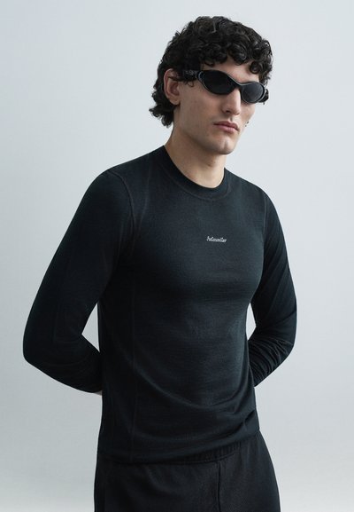 Black long-sleeve top with a fitted design, made from a smooth fabric. Features a small logo on the chest and round neckline.