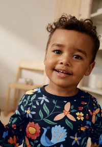 Donkerblauw shirt met lange mouwen, voorzien van levendige bloemen- en pauwenmotieven. Gemaakt van zacht materiaal met een ronde hals en een ontspannen pasvorm.