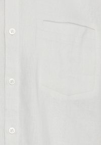 Chemise en lin blanc avec une fermeture à boutons, deux boutons, une poche poitrine et un design de tissu texturé.