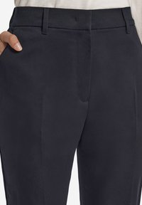 Marinebyxor i slätt tyg med rak passform, sidofickor och en platt front. Midjebandet sitter bekvämt vid den naturliga midjan.