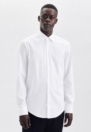 Witte lange mouwen shirt van glad katoen. Voorzien van een klassieke kraag, knopen aan de voorkant en een ronde zoom.