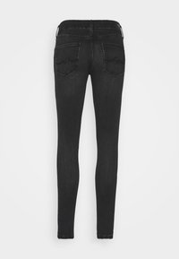 Jeans negros ajustados con una cintura de altura media, bolsillos traseros con costuras curvas y una textura de denim suave.