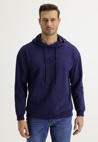 Felpa con cappuccio blu navy con la scritta "ENJOY" in rilievo sulla parte anteriore, dotata di tasca a marsupio e lacci, realizzata in un tessuto morbido.