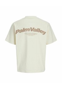 Bijela pamučna majica opuštenog kroja, s velikim natpisom "Palm Valley" u smeškastoj boji na leđima i dodatnim printanim detaljima ispod.