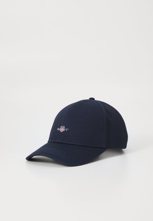 Navy blue cotton baseball cap with a curved brim, embroidered logo on front, and contrasting stitching details. Adjustable strap at back.