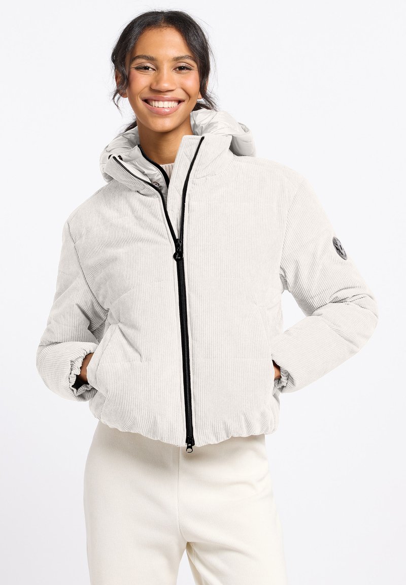 Lichtgrijze corduroy pufferjack met capuchon, uitgerust met een voorkeursrits, elastische boorden en een logopatch op de mouw. Gladde textuur.