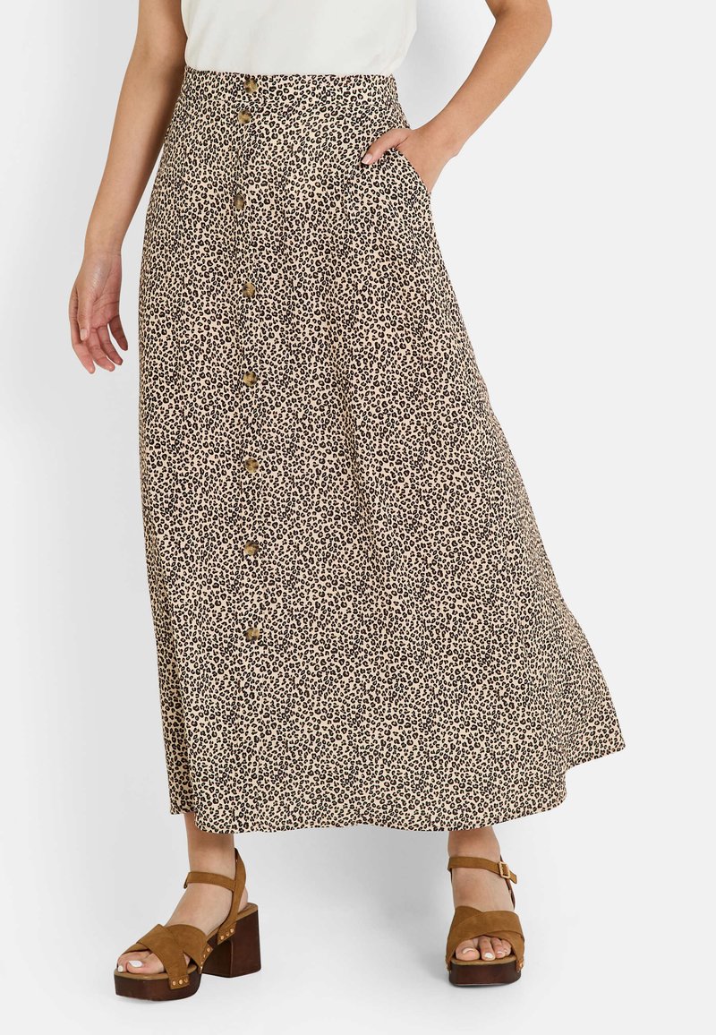 Falda midi de leopardo con un frente de botones, bolsillos y una silueta en A. La tela es ligera y de textura suave. Sandalias de plataforma marrones.