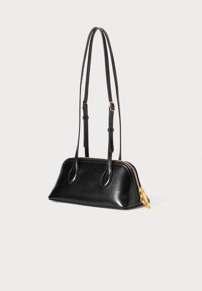 Bolsa de mão em couro preto com um design estruturado, fecho com zíper, duas alças ajustáveis e detalhes em metal dourado. Textura suave e forma elegante.