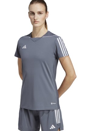 Maglietta atletica grigia a maniche corte, design a V, con dettagli in rete sulle spalle e tre strisce bianche su entrambe le maniche.