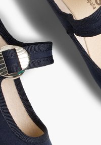 Bailarinas de color azul marino con una correa de tela y un hebilla circular en tono plateado. Suave forro interior con una textura lisa y suela resistente.