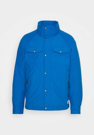 Blaue isolierte Jacke mit hohem Kragen, zwei Brusttaschen, Druckknopfverschlüssen und seitlichen Reißverschlüssen, gefertigt aus einem glatten, strapazierfähigen Stoff.