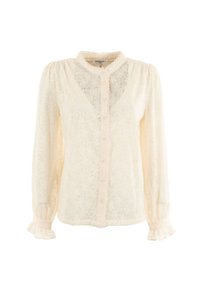 Blusa in pizzo color avorio con colletto alto, chiusura a bottoni e maniche lunghe con polsini a frange. Texture delicata e motivo floreale.