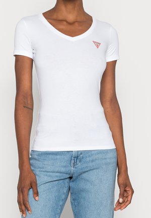 T-shirt blanc ajusté avec un col en V et des manches courtes, arborant un petit logo triangulaire rouge sur le côté gauche de la poitrine. Texture lisse.