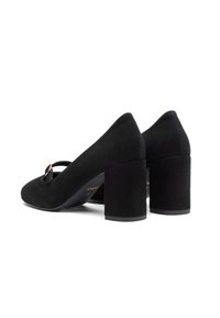 Melnas zamša augstpapēžu kurpes ar kvadrātu papēdi un siksniņu pāri priekšai, kurai ir neliels metālisks akcenti.