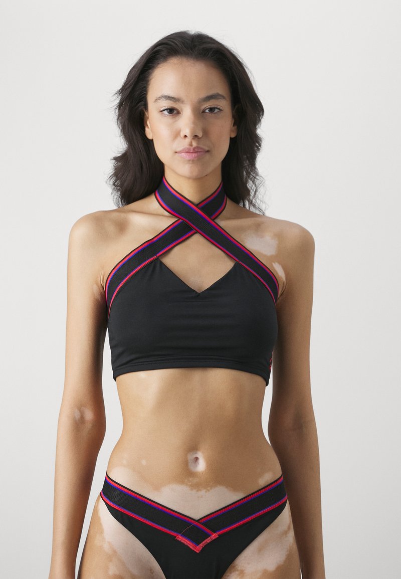 Un haut de bikini noir avec des bretelles entrecroisées en rouge et rose, présentant un design en v. Bas de bikini assorti avec un détail de bretelles similaire à la taille.