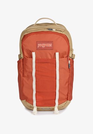 Dwukolorowy beżowo-płonący pomarańczowy plecak Jansport z wieloma przegrodami, przednimi paskami i bocznymi kieszeniami na białym tle.