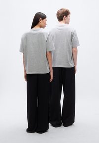 Γκρι κοντομάνικα μπλουζάκια από βαμβακερό μείγμα, συνδυασμένα με φαρδιά μαύρα παντελόνια. Απλός σχεδιασμός χωρίς εμφανή λογότυπα ή μοτίβα.