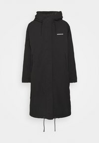 Parka nera lunga con cappuccio, dotata di zip frontale, due tasche laterali e orlo regolabile con coulisse. Tessuto morbido e liscio.