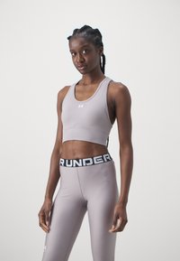 Top corto sport grigio in tessuto testurizzato con design racerback, abbinato a leggings grigi con una vita nera riportante la scritta "RUNNER".