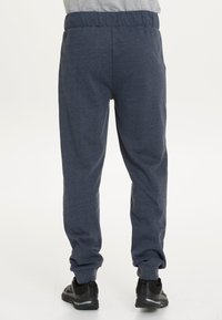 Marineblaue Jogginghose mit weicher Textur, elastischem Bund und Bündchen an den Knöcheln. Verfügt über Seitentaschen und eine schlanke Passform.