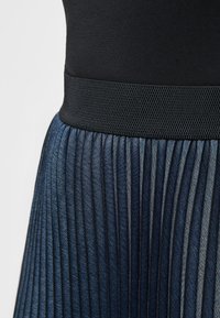 Elastische taille geplooide rok in donkerblauwe denim met een subtiele glans; heeft verticale strepen en een gestructureerde zwarte tailleband.