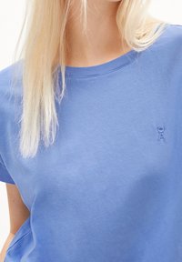 Jasnoniebieska bawełniana koszulka z okrągłym dekoltem i krótkimi rękawami. Na piersi małe, haftowane logo. Miękka w dotyku.