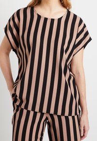 Blusa a rayas en negro y rosa claro, con cuello redondo, mangas cortas y un corte relajado. La tela parece ligera y tiene una textura suave.