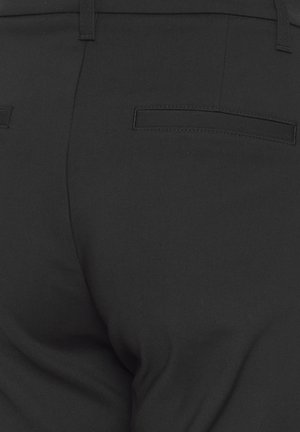 Zwarte, op maat gemaakte broek met twee achterste insteekzakken en riemlussen, gezien vanaf de taille naar beneden.