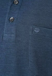 Marineblauwe polo met een gestructureerde stof, twee knopen en een klein borstzakje met een subtiele logo-detail.
