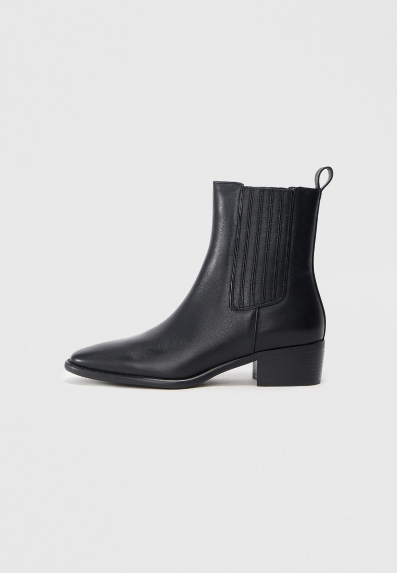 Schwarzer Knöchelstiefel aus glattem Leder mit spitzem Zeh, elastischen seitlichen Einsätzen und kleinem Blockabsatz. Mit einer Schlaufe für ein einfaches Anziehen.