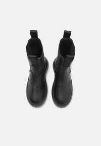 Bottines en cuir noir avec une finition lisse, panneaux latéraux élastiques et semelles en caoutchouc nervuré. Comprend des languettes pour un enfilage facile.