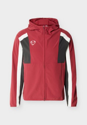 Veste à capuche rouge à fermeture éclair intégrale avec des panneaux noirs et blancs sur les manches et la poitrine, arborant un petit logo Nike sur le côté gauche de la poitrine.