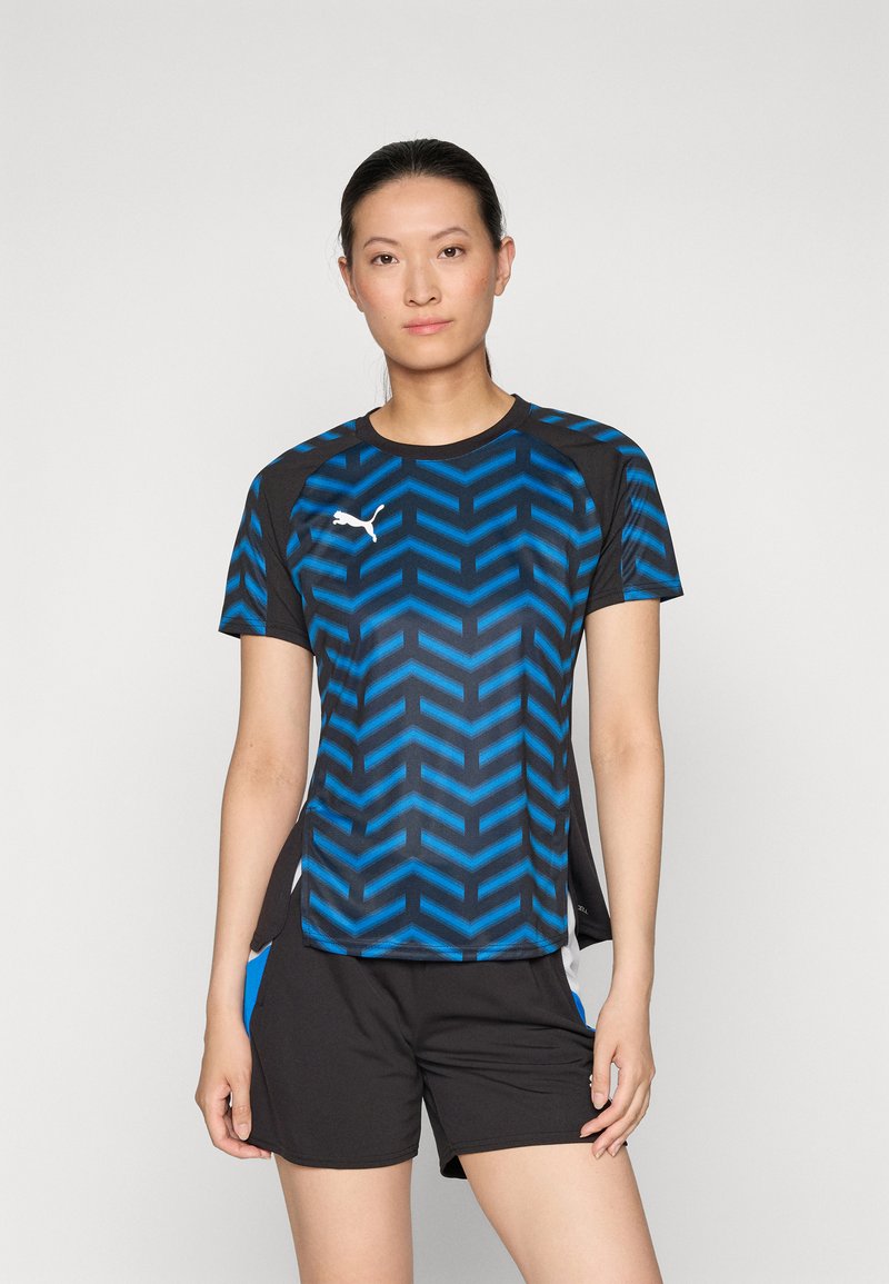 Sinine ja must sportlik T-särk, millel on ševronimuster, ümmargune kaelus, lühikesed varrukad ja külgedel lõhed. Rinna peal valge Puma logo.