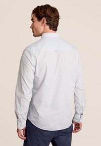 Langarm overhemd met een lichtblauw, rood en wit geometrisch patroon, voorzien van een button-down kraag en knoopmanchetten.