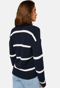 Marineblauer gestrickter Pullover mit weißen horizontalen Streifen, mit lockerer Passform und weiten Ärmeln. Weiche Textur, gerippter Halsausschnitt und Saum.