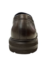 Bruine leren schoen met een ronde achterkant, minimale stiksels en een dikke zwarte zool. Beschikt over een soepele, glanzende afwerking en een comfortabele kraag.