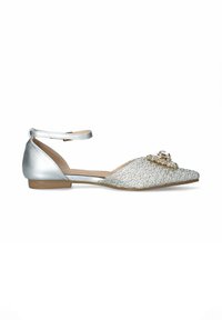 Scarpa piatta con tacco in pelle argento, parte superiore intrecciata in argento, punta affilata e un accento decorativo di gemma sul davanti. Cinghietta alla caviglia inclusa.