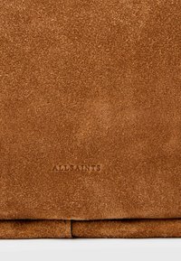 Brūna zamša soma ar mīkstu tekstūru, kurai apakšā ir iegravēts "ALLSAINTS" logo. Gluda, salokāma forma ar skaidrām līnijām.