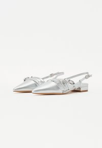 Hõbedased sünteetilised slingback kingad, millel on terav nina, dekoratiivsed rihmad ja madal plokkkand. Sile tekstuur ja minimaalsed metalldetailid.