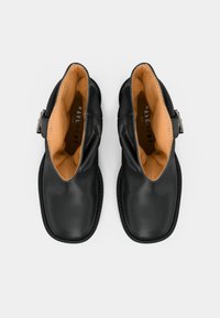 Must rebenahast pahklu saapad sileda viimistlusega, ümarate varvastega ja kontrastse pruunika siseküljega. Omavad külgklambriga detaili.