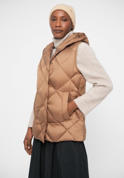 Gilet matelassé marron avec capuche, doté de poches latérales. Porté sur un pull gris clair. Fond blanc uni.
