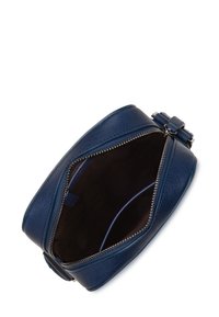 Borsa rotonda in pelle blu con chiusura a zip, caratterizzata da una superficie liscia e un interno in tessuto scuro visibile attraverso l'apertura superiore.